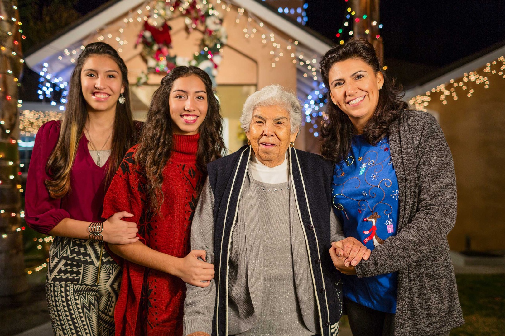 Grandmother with her daughter and granddaughters standing together during the Christmas season.